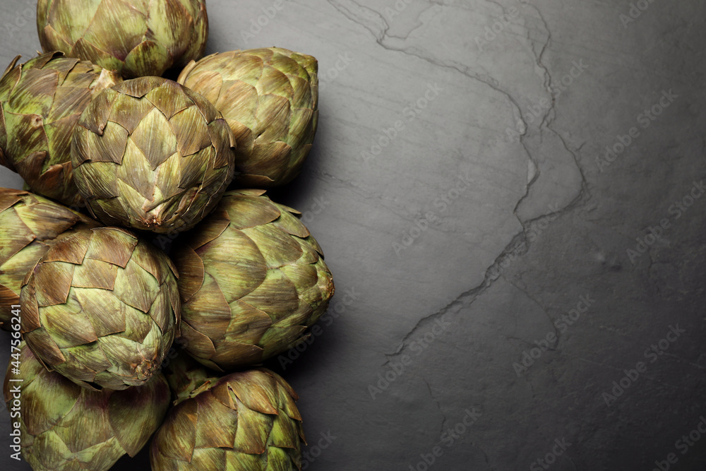 Fototapeta premium Fresh raw artichokes on black table, flat lay. Space for text
