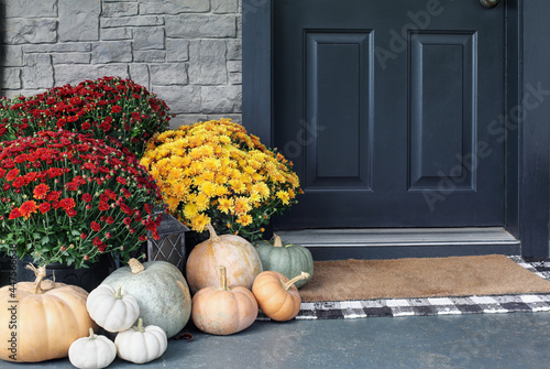 Heirloom white, orange and grey pumpkins with colorful mums sitting by front door.