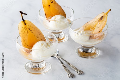 Close up of glass dishes filled with poached pears served with ice cream. photo