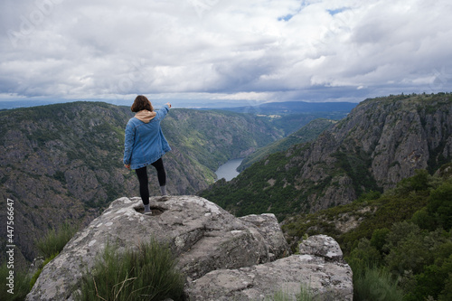 Woman on a rock pointing to the landscape of Galicia, Spain.