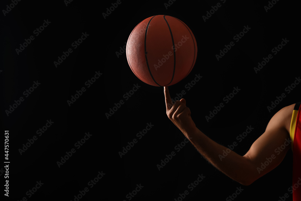 Basketball player with spinning ball on black background, closeup. Space for text