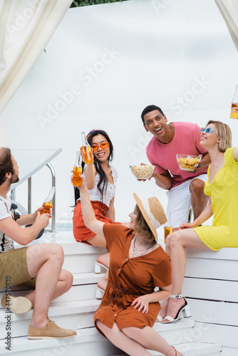 joyful multiethnic friends smiling during beer party with snacks in patio © LIGHTFIELD STUDIOS