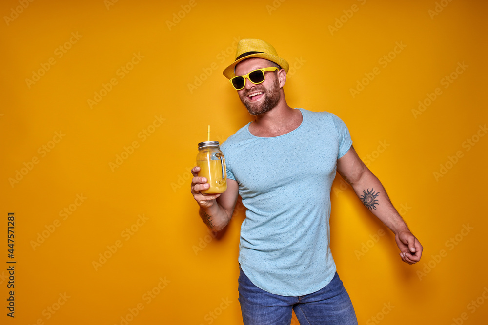 Creative male in sunglasses and summer clothes, stylish hat standing relaxed and drinking from creative cocktail bottle Creative male in sunglasses and summer clothes, stylish hat standing relaxed and drinking from creative cocktail bottle