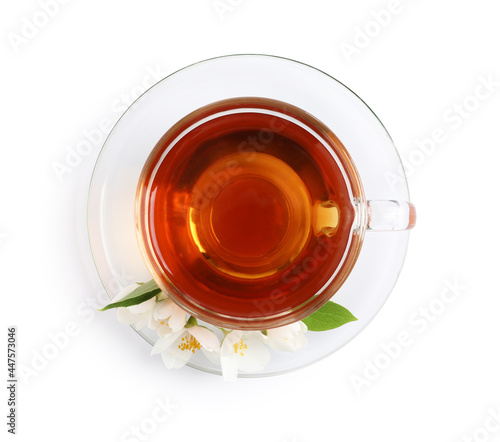 Glass cup of aromatic jasmine tea and fresh flowers on white background, top view