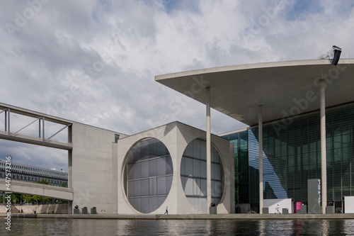 Outdoor exterior view of Marie-Elisabeth-Lüders-Haus, Federal government office, with rough concrete facade and big circle hole, along Spree River and pedestrian bridge in Berlin, Germany. photo