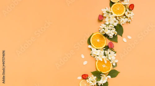 Citrus and strawberry slices with garden jasmine flowers on an orange background. Summer background with pattern. Banner with copy space photo