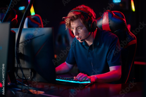 Game of a young guy wearing headphones in a video game in a computer club