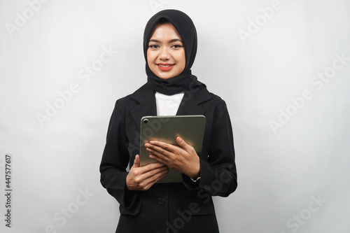 Beautiful young asian muslim business woman confident and smiling, with hands holding tablet, time to work, productive time, isolated on gray background