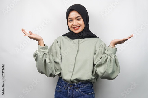 Beautiful young asian muslim woman confident and smiling, with open arms, presenting something, presenting product, isolated on gray background