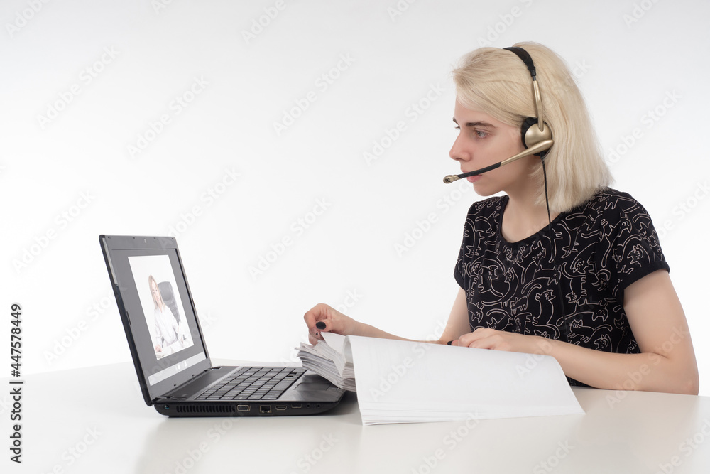 Call center operator during work. Call center operator next to laptop. Blonde girl works for cameramen. She is a call center employee. Video support worker. Office worker on a white background. Call center operator during work. Call center operator next to laptop. Blonde girl works for cameramen. She is a call center employee. Video support worker. Office worker on a white background.