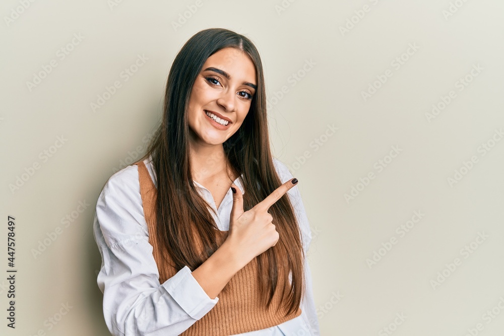 Beautiful brunette young woman wearing casual clothes cheerful with a smile of face pointing with hand and finger up to the side with happy and natural expression on face Beautiful brunette young woman wearing casual clothes cheerful with a smile of face pointing with hand and finger up to the side with happy and natural expression on face