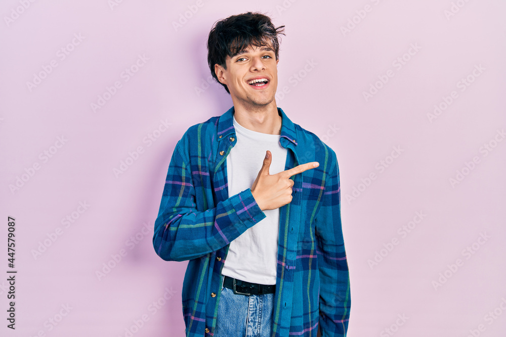 Handsome hipster young man wearing casual white t shirt and vintage shirt cheerful with a smile of face pointing with hand and finger up to the side with happy and natural expression on face Handsome hipster young man wearing casual white t shirt and vintage shirt cheerful with a smile of face pointing with hand and finger up to the side with happy and natural expression on face