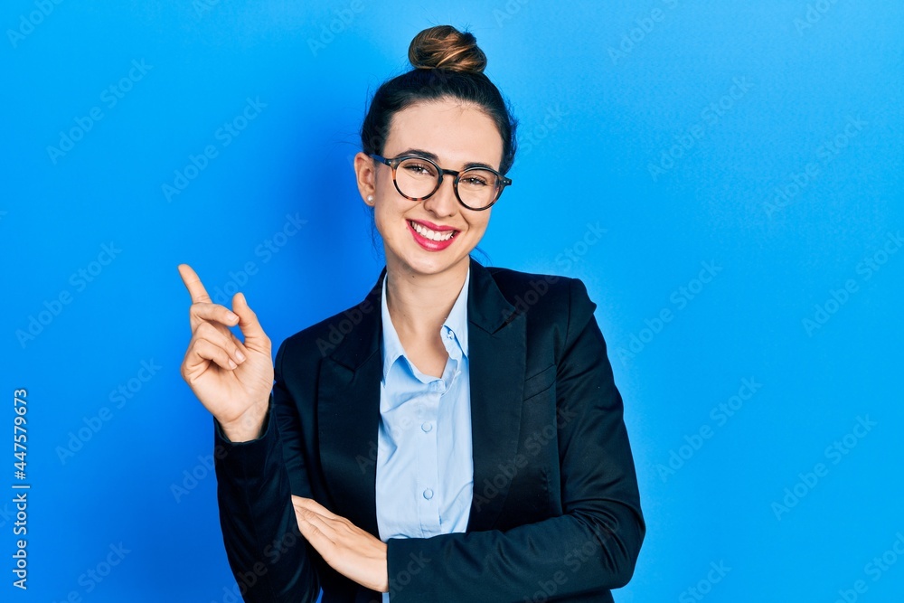 Young hispanic girl wearing business clothes and glasses with a big smile on face, pointing with hand and finger to the side looking at the camera. Young hispanic girl wearing business clothes and glasses with a big smile on face, pointing with hand and finger to the side looking at the camera.