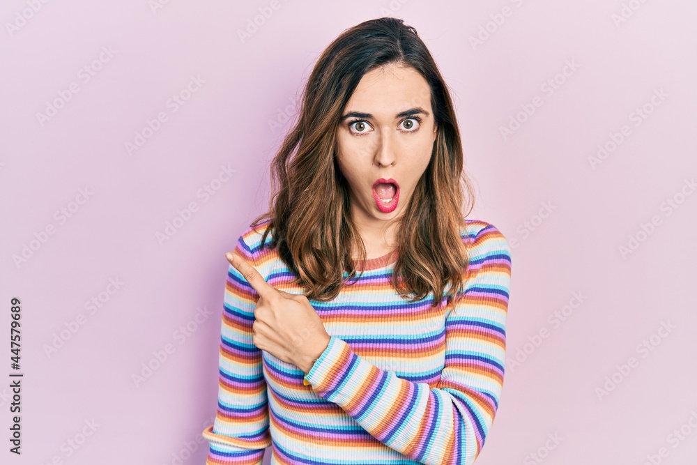 Fototapeta premium Young hispanic girl wearing casual clothes surprised pointing with finger to the side, open mouth amazed expression.