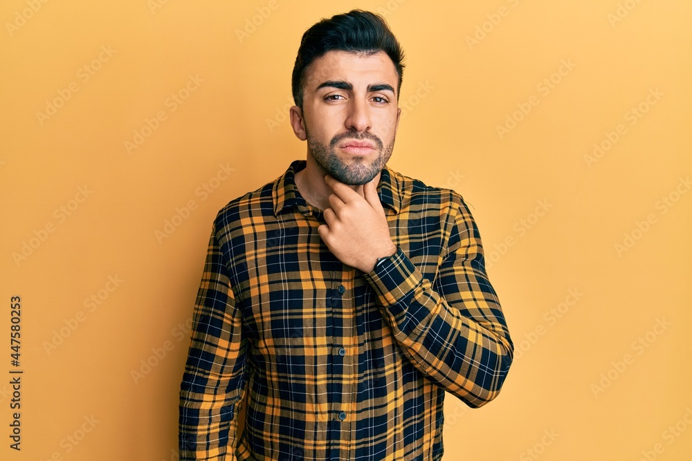 Young hispanic man wearing casual clothes touching painful neck, sore throat for flu, clod and infection