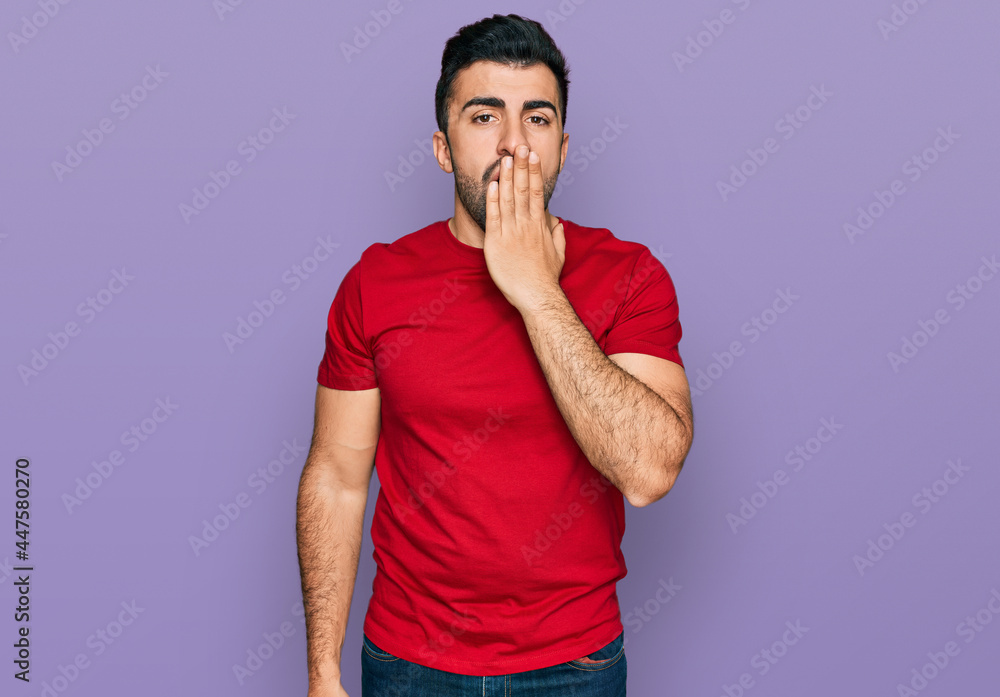 Hispanic man with beard wearing casual red t shirt bored yawning tired covering mouth with hand. restless and sleepiness. Hispanic man with beard wearing casual red t shirt bored yawning tired covering mouth with hand. restless and sleepiness.