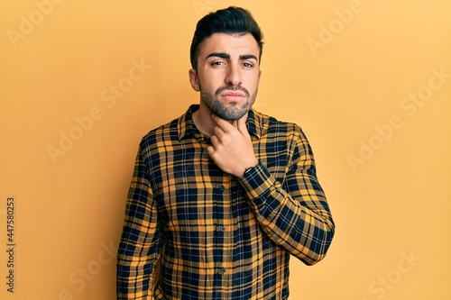 Young hispanic man wearing casual clothes touching painful neck, sore throat for flu, clod and infection