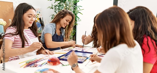 Group of women smiling happy drawing sitting on the table at art studio.