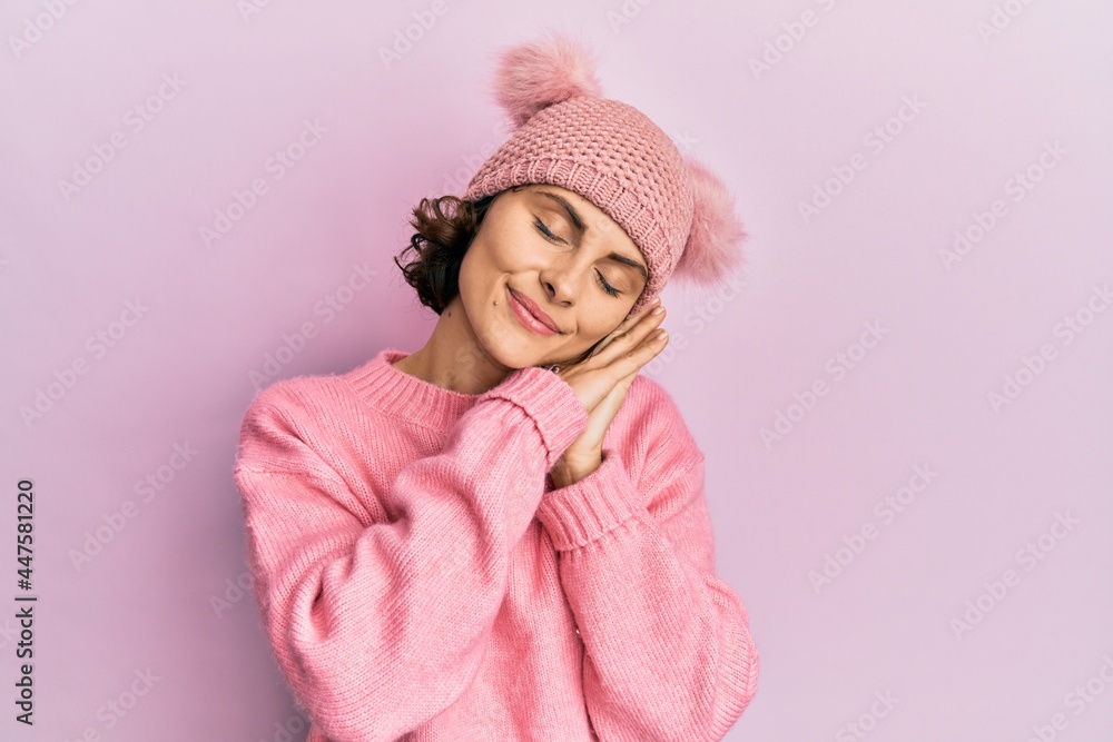 Young brunette woman wearing cute wool cap sleeping tired dreaming and posing with hands together while smiling with closed eyes. Young brunette woman wearing cute wool cap sleeping tired dreaming and posing with hands together while smiling with closed eyes.