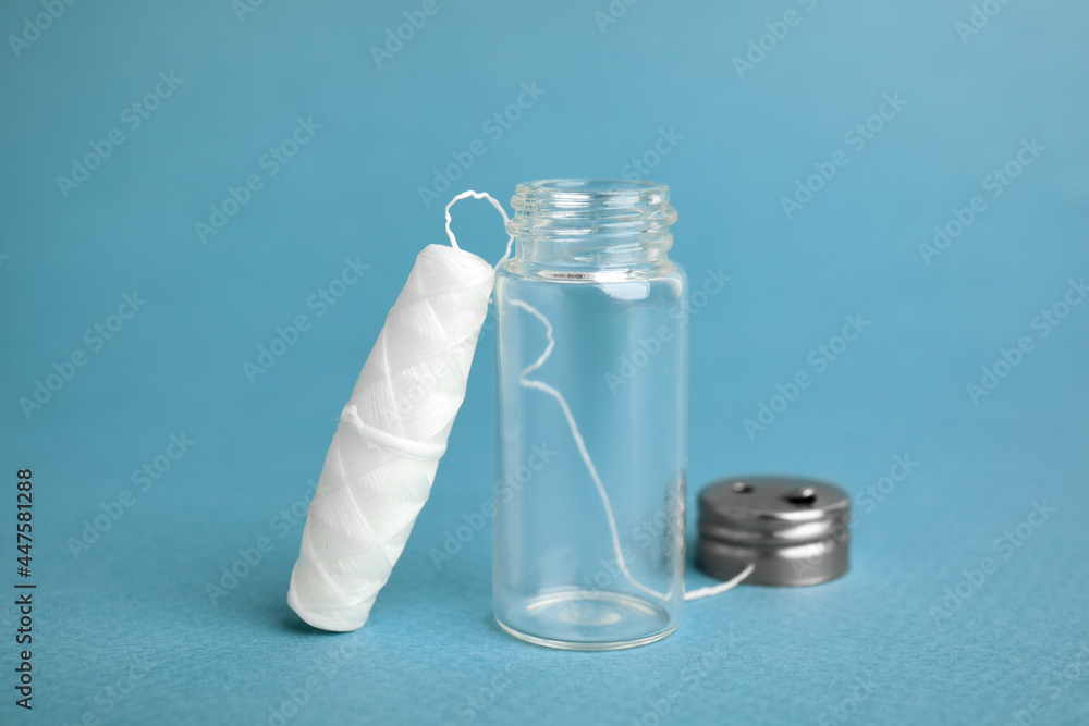 Biodegradable dental floss and glass jar on light blue background Biodegradable dental floss and glass jar on light blue background