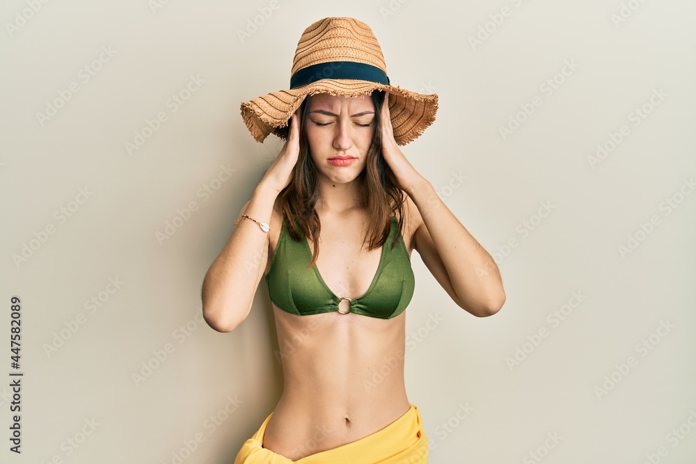 Young brunette woman wearing bikini with hand on head for pain in head because stress. suffering migraine. Young brunette woman wearing bikini with hand on head for pain in head because stress. suffering migraine.