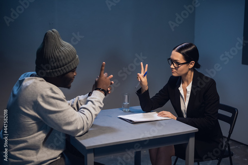 A black guy listens to his rights from a civil lawyer at a table in a visiting room in a state prison