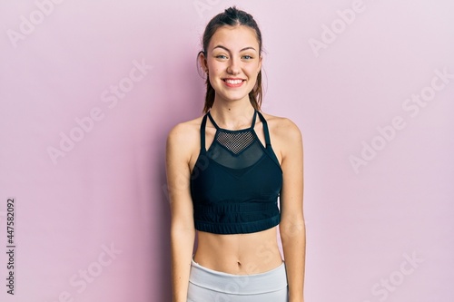 Young brunette woman wearing sportswear looking positive and happy standing and smiling with a confident smile showing teeth