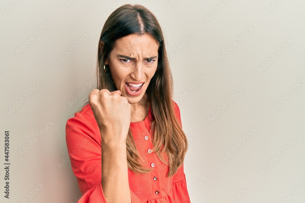 Fototapeta premium Young beautiful woman wearing casual clothes angry and mad raising fist frustrated and furious while shouting with anger. rage and aggressive concept.