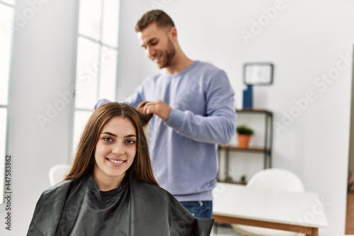 Young man cutting hair his girlfriend at home.