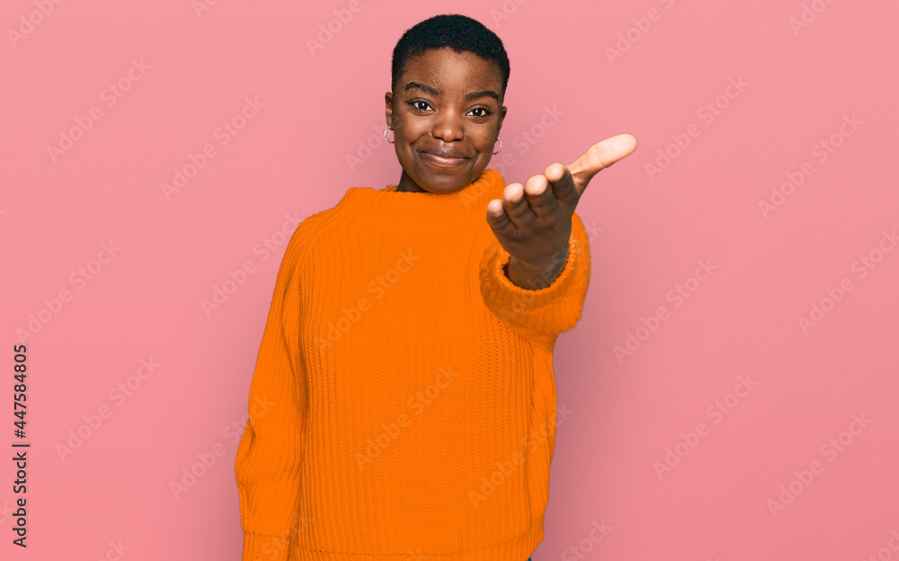 Young african american woman wearing casual clothes smiling friendly offering handshake as greeting and welcoming. successful business. Young african american woman wearing casual clothes smiling friendly offering handshake as greeting and welcoming. successful business.
