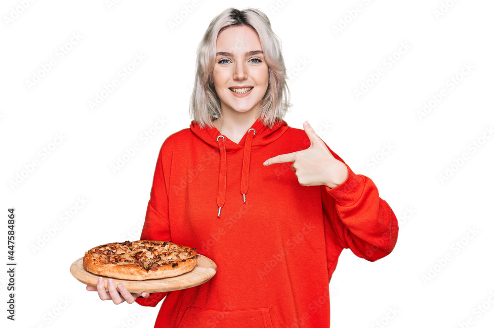 Young blonde girl holding italian pizza pointing finger to one self smiling happy and proud Young blonde girl holding italian pizza pointing finger to one self smiling happy and proud