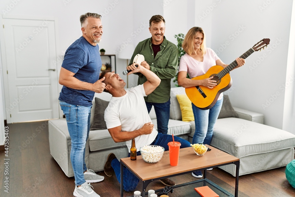 Group of middle age friends on party singing and playing guitar at home. Group of middle age friends on party singing and playing guitar at home.