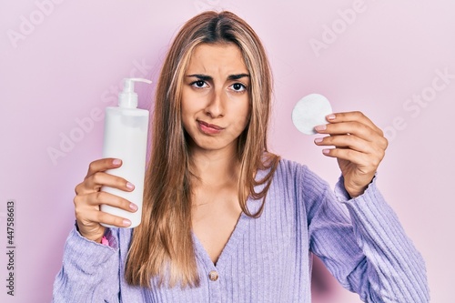 Konstfotografi Beautiful hispanic woman holding cotton pad and make up remover skeptic and nervous, frowning upset because of problem