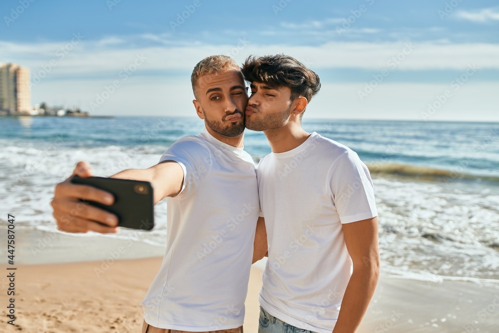 Young gay couple smiling happy making selfie by the smartphone at the beach. Young gay couple smiling happy making selfie by the smartphone at the beach.