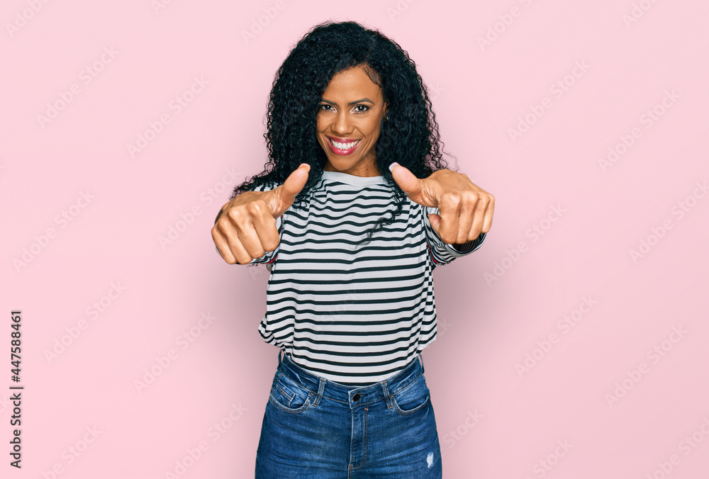 Middle age african american woman wearing casual clothes approving doing positive gesture with hand, thumbs up smiling and happy for success. winner gesture. Middle age african american woman wearing casual clothes approving doing positive gesture with hand, thumbs up smiling and happy for success. winner gesture.