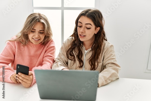 Young couple smiling happy working using laptop and smartphone at home.