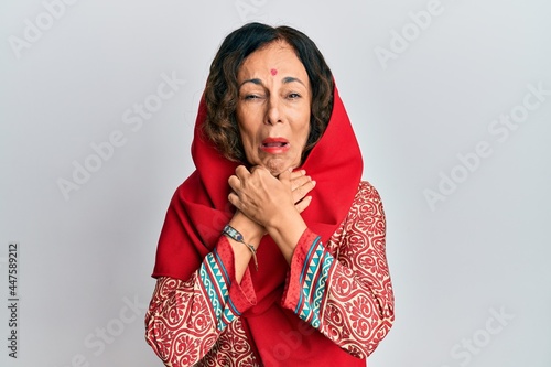 Middle age hispanic woman wearing tradition sherwani saree clothes shouting and suffocate because painful strangle. health problem. asphyxiate and suicide concept.