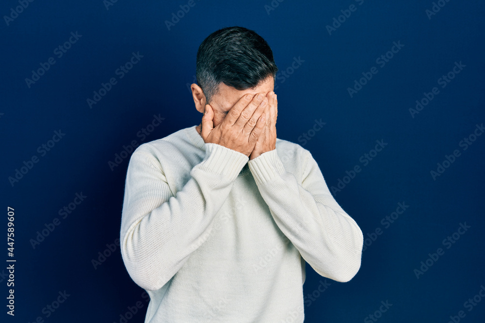 Young hispanic man wearing casual clothes with sad expression covering face with hands while crying. depression concept.
