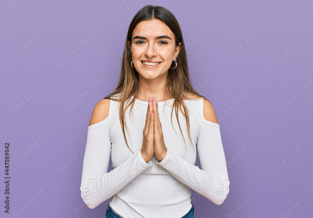 Young hispanic woman wearing casual clothes praying with hands together asking for forgiveness smiling confident. Young hispanic woman wearing casual clothes praying with hands together asking for forgiveness smiling confident.