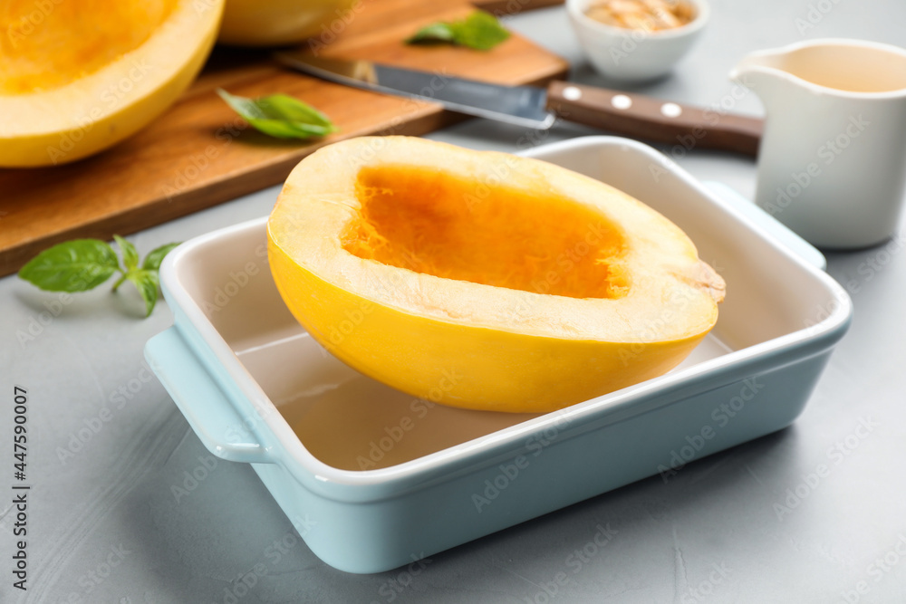 Raw spaghetti squash half in baking dish on light table Raw spaghetti squash half in baking dish on light table