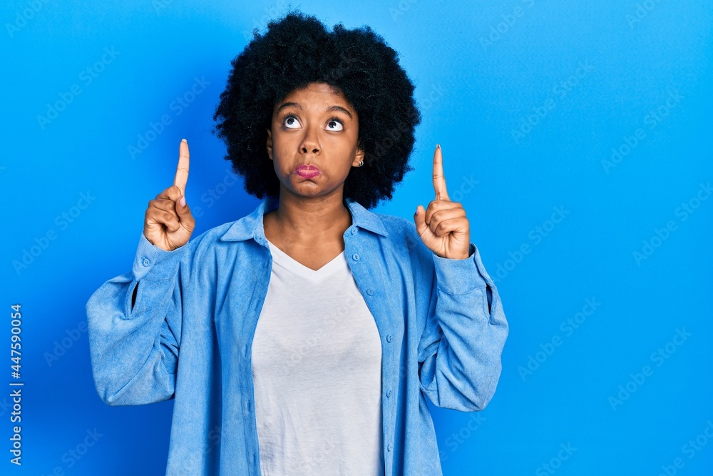 Young african american woman wearing casual clothes pointing up looking sad and upset, indicating direction with fingers, unhappy and depressed. Young african american woman wearing casual clothes pointing up looking sad and upset, indicating direction with fingers, unhappy and depressed.