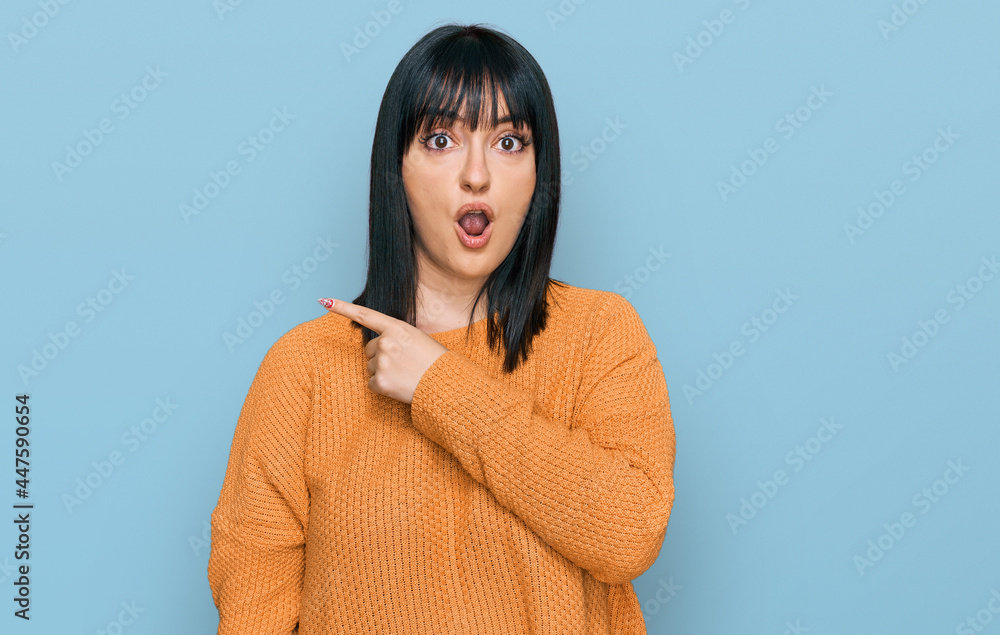 Fototapeta premium Young hispanic woman wearing casual clothes surprised pointing with finger to the side, open mouth amazed expression.