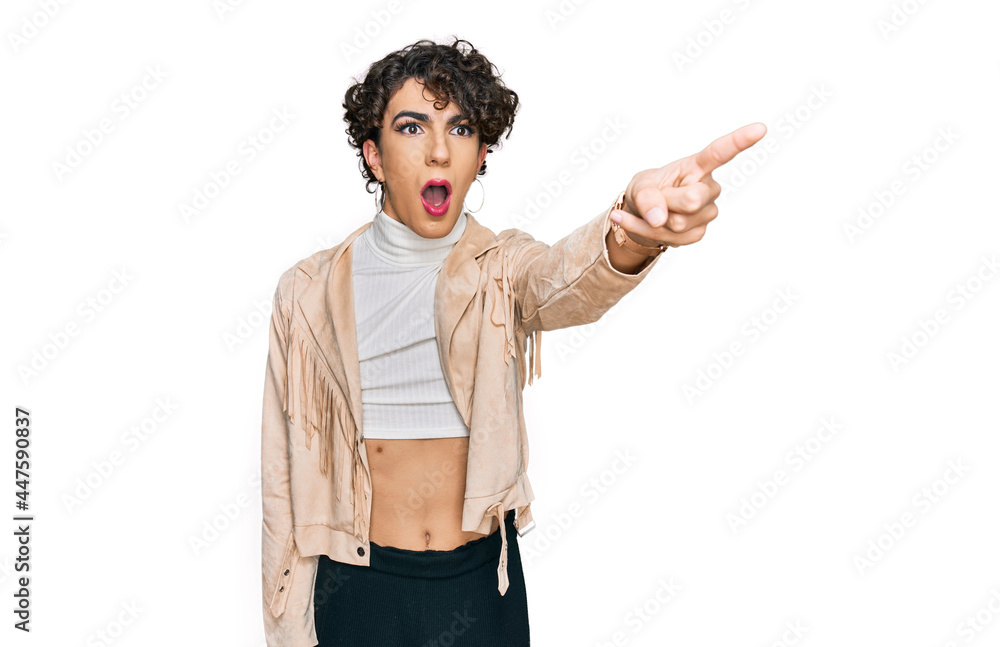 Handsome man wearing make up and woman clothes pointing with finger surprised ahead, open mouth amazed expression, something on the front Handsome man wearing make up and woman clothes pointing with finger surprised ahead, open mouth amazed expression, something on the front