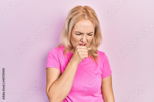 Young blonde woman wearing casual pink t shirt feeling unwell and coughing as symptom for cold or bronchitis. health care concept.