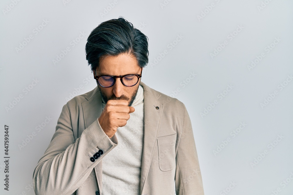 Young hispanic man wearing business jacket and glasses feeling unwell and coughing as symptom for cold or bronchitis. health care concept. Young hispanic man wearing business jacket and glasses feeling unwell and coughing as symptom for cold or bronchitis. health care concept.
