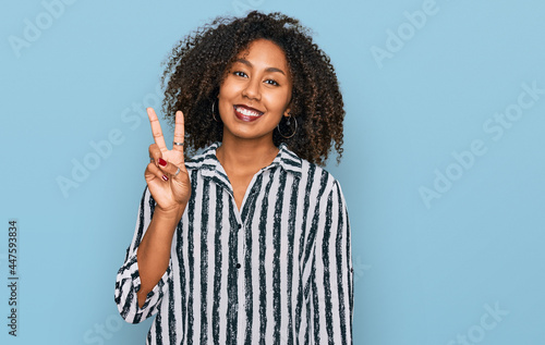 Young african american girl wearing casual clothes showing and pointing up with fingers number two while smiling confident and happy. © Krakenimages.com