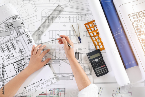Architect Drawing Blueprint At Desk In Office photo