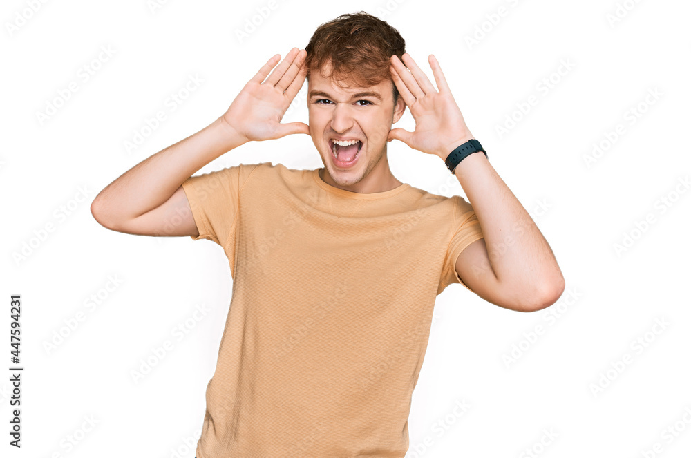 Young caucasian man wearing casual clothes smiling cheerful playing peek a boo with hands showing face. surprised and exited