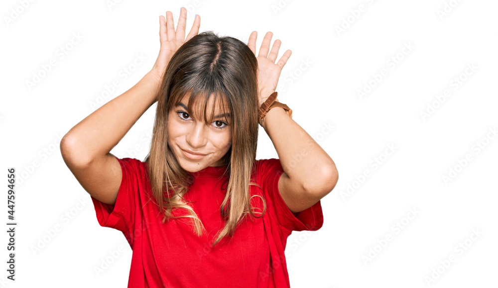 Teenager caucasian girl wearing casual red t shirt doing bunny ears gesture with hands palms looking cynical and skeptical. easter rabbit concept. Teenager caucasian girl wearing casual red t shirt doing bunny ears gesture with hands palms looking cynical and skeptical. easter rabbit concept.