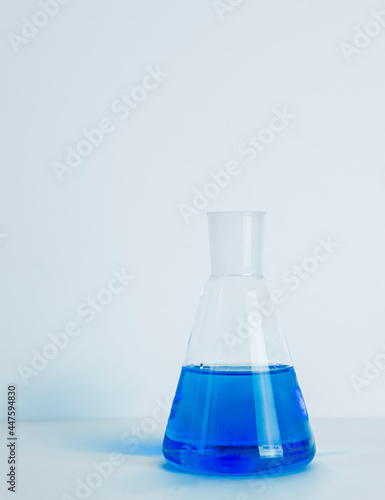 Laboratory glass Erlenmeyer conical flask filled with blue chemical liquid for a chemistry experiment in a science research lab,COPY SPACE